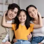 une petite fille heureuse tenant par les bras ses parents